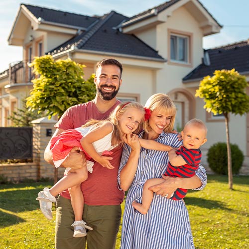 happy family standing outside in front of their new home